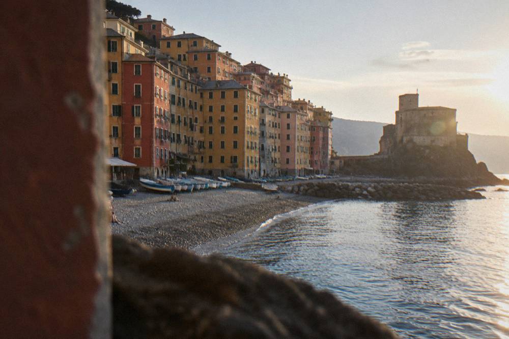 Colourful houses above a small pebble beach in Camogli seen from the water